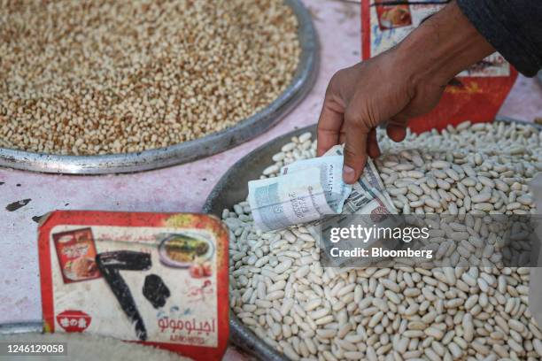 Customer hands over Egyptian pound banknotes for a purchase at Al-Monira food market in the Imbaba district of Giza, Egypt, on Saturday, Jan. 7,...