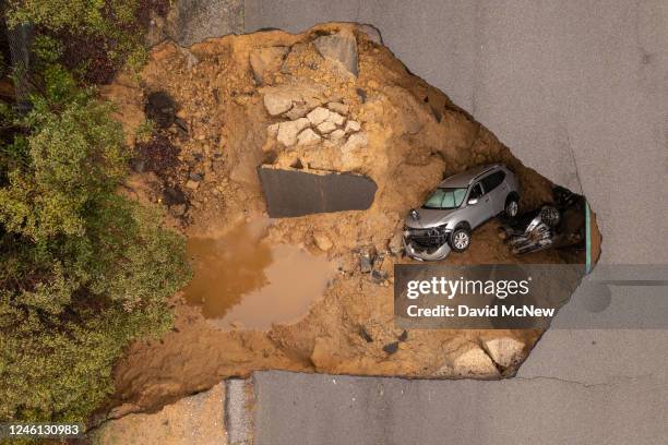 In an aerial view, a car and a pickup truck are seen inside a sinkhole as another storm created by a series of atmospheric rivers inundates...