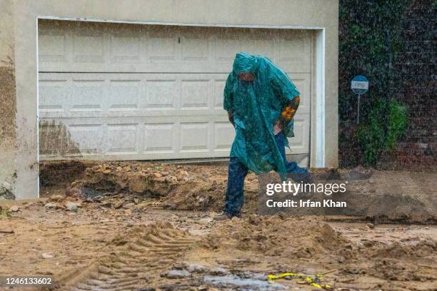 Studio City, CA A man in heavy rain jumps over mudslide and rushing water from hillside in front of his home at 3700 block of North Fredonia Drive on...