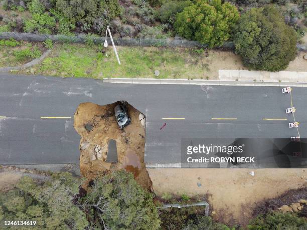 This aerial view shows two cars siting in a large sinkhole that opened during a day of relentless rain, January 10, 2023 in the Chatsworth...