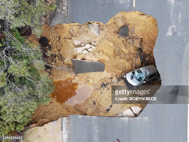This aerial view shows two cars siting in a large sinkhole that opened during a day of relentless rain, January 10, 2023 in the Chatsworth...