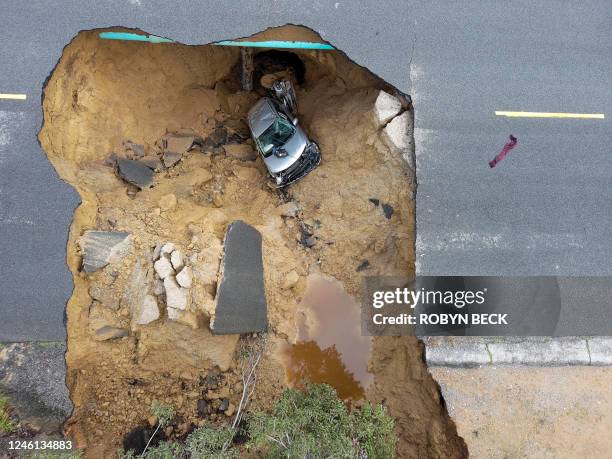 This aerial view shows two cars siting in a large sinkhole that opened during a day of relentless rain, January 10, 2023 in the Chatsworth...