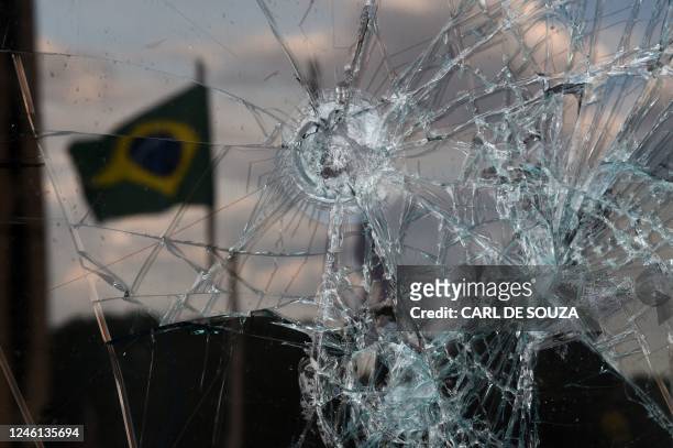 Brazilian flag is reflected on a broken window of the Supreme Court building in Brasilia on January 10 two days after thousands of supporters of...
