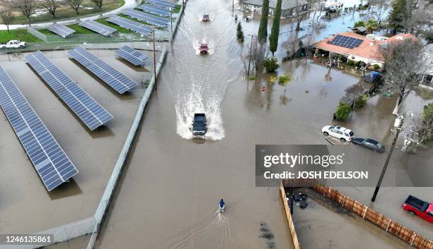 This aerial view shows cars driving through a flooded roadway in Planada, California, as an "atmospheric river" continues on January 10, 2023....