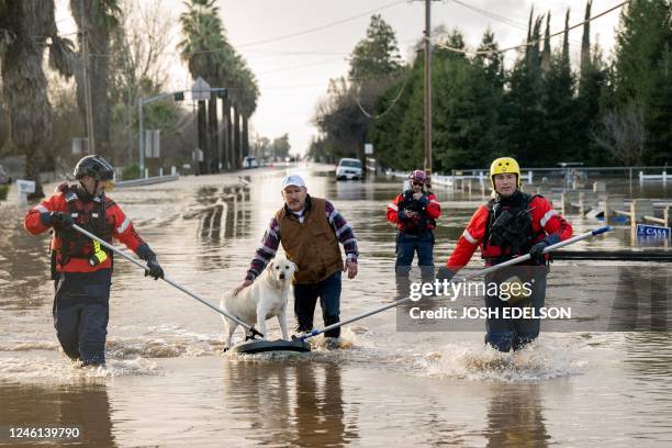 San Diego firefighters help Humberto Maciel rescue his dog from his flooded home in Merced, California, on January 10, 2023. - Relentless storms were...