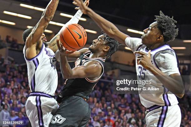 John-Michael Wright of the Oklahoma State Cowboys drives to the basket between Nae'Qwan Tomlin and Desi Sills of the Kansas State Wildcats in the...