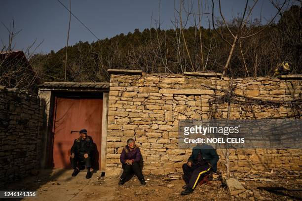 This photo taken on January 7, 2023 shows elderly people sitting in front of a house in a rural area in Tai'an, China's eastern Shandong province. -...