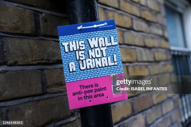 Photograph taken on January 11, 2023 shows a board indicating that the walls of the area are covered by anti-pee paint, in Soho, central London. -...