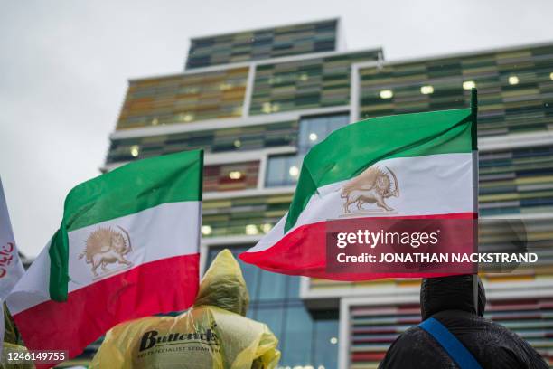 Protesters wave a historic Iranian flag with the Lion and Sun symbol as they gather outside of the Appeals Court building in Sollentuna, north of...