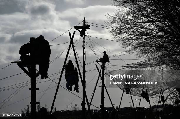 Environmentalists sit on so-called tripods in the village of Luetzerath, western Germany, on January 11 as police started the evacuation of anti-coal...