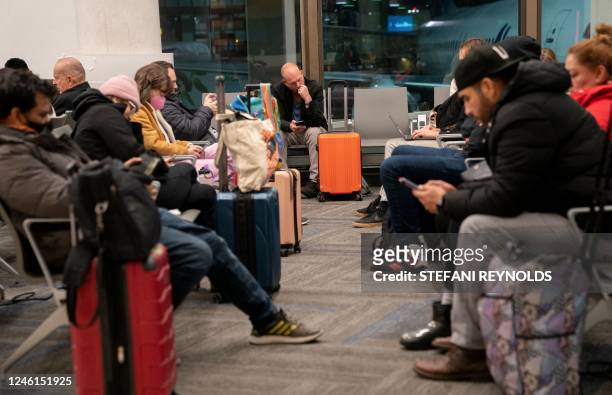 Travelers wait to hear if their flight will depart on time, at Los Angeles International Airport in Los Angeles, on January 11, 2023. - The US...