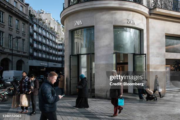 Shoppers pass a Zara clothing store, operated by Inditex SA, on the first day of the winter sales on the Champs-Elysee avenue in Paris, France, on...
