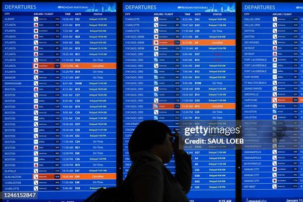 Travelers looks at a flight information display listing cancelled and delayed flights due to an FAA outage that grounded flights across the US at...