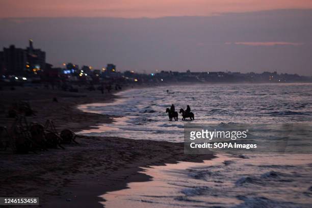 Palestinians with their horses seen at the Mediterranean beach during a pink-hued sunset in Gaza City.