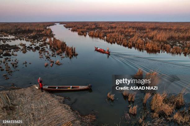 This picture taken on January 11, 2023 shows an aerial view of a man standing on a boat cruising in Iraq's southern marshes of Chibayish in Dhi Qar...