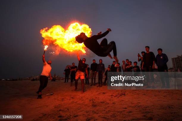 Palestinian youth show skills with perform fire breathing and practice parkour skills on Gaza Beach during sunset, on January 11, 2023.