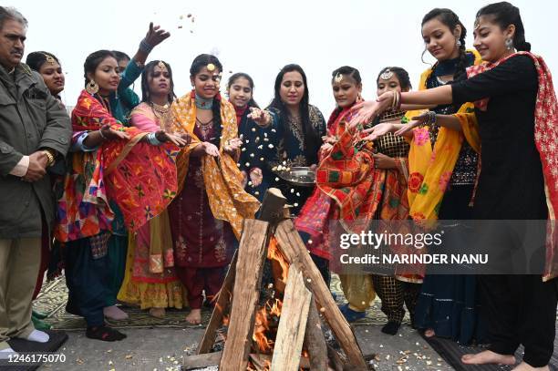 Students throw popcorn, groundnuts and sweets in a bonfire during Lohri festival celebrations in Amritsar on January 12, 2023.