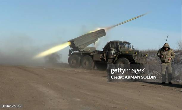 This grab taken from AFP video footage shows a member of Ukraine's military looking away as a BM-21'Grad' MLRS 122mm rocket launcher fires on the...