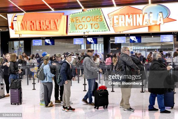 Travelers stand in line to pass through a security checkpoint at Terminal A at Newark Liberty International Airport in Newark, New Jersey, US, on...