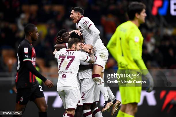Michel Adopo of Torino FC celebrates with his teammates after scoring a goal as Pierre Kalulu and Ciprian Tatarusanu of AC Milan look dejected during...