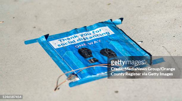 Social distancing sign is taped to the sidewalk in front of the AT&T call center in Tustin, CA on Monday, November 16, 2020. About 30 employees...