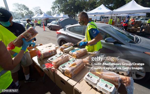 Volunteer loads food into a car during a drive-thru grocery distribution at Mile Square Park in Fountain Valley, CA on Wednesday, November 4, 2020....