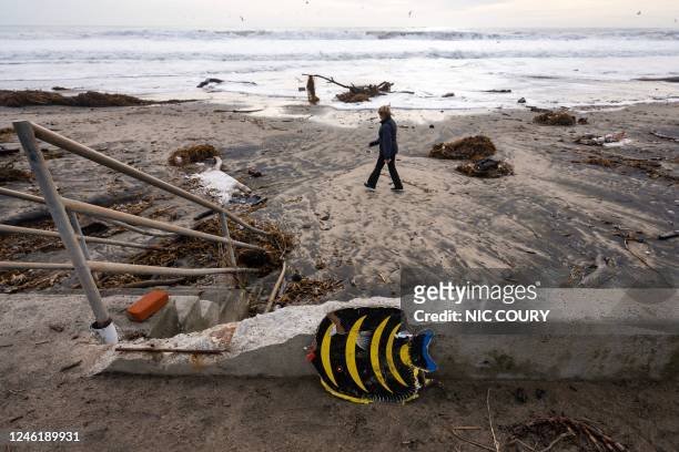 Woman walks on Rio Del Mar beach, covered with storm debris, in Aptos, California on January 12, 2023. - A "relentless parade of cyclones" hitting...