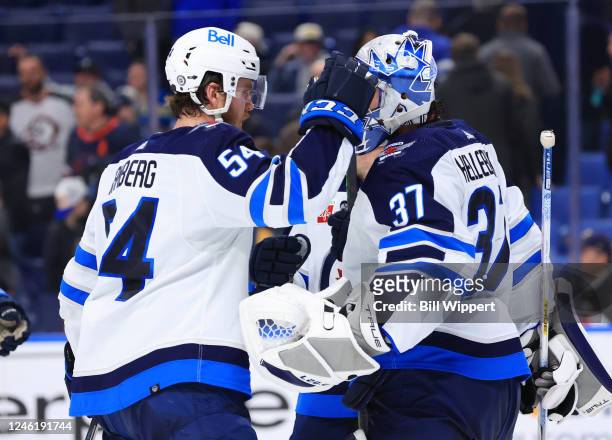 Connor Hellebuyck and Dylan Samberg of the Winnipeg Jets celebrate a 4-2 victory over the Buffalo Sabres after an NHL game on January 12, 2023 at...