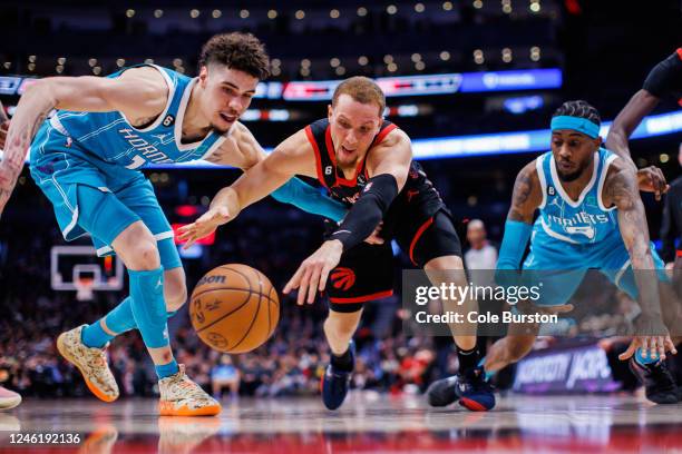 Malachi Flynn of the Toronto Raptors reaches for a loose ball against LaMelo Ball of the Charlotte Hornets during the second half at Scotiabank Arena...