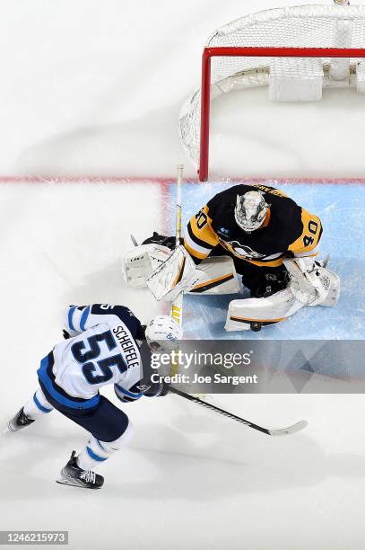 Dustin Tokarski of the Pittsburgh Penguins makes a save against Mark Scheifele of the Winnipeg Jets at PPG PAINTS Arena on January 13, 2023 in...