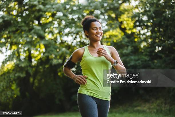 mulher atlética africana adulta média correndo na natureza - jogging - fotografias e filmes do acervo