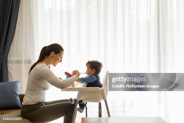 mother feeding her baby boy - mother baby food stock pictures, royalty-free photos & images