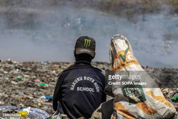 Waste picker ponders as he rests looking towards burning garbage at Nakuru main dumping yard. Since waste is rarely segregated and is heavily mixed...