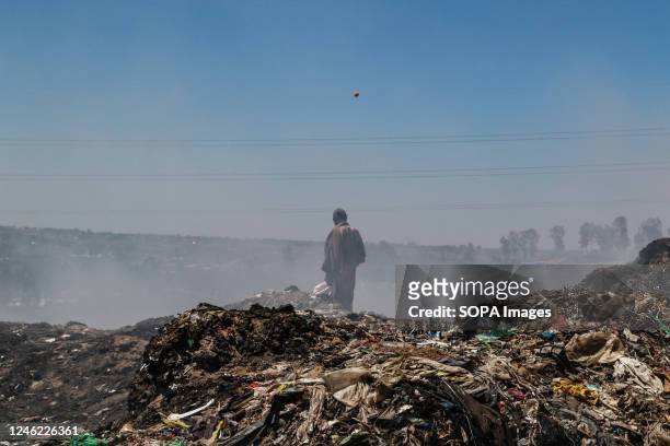 Waste picker recovers waste for recycling amidst heavy smoke from burning garbage at the Nakuru main dumping yard. Since waste is rarely segregated...