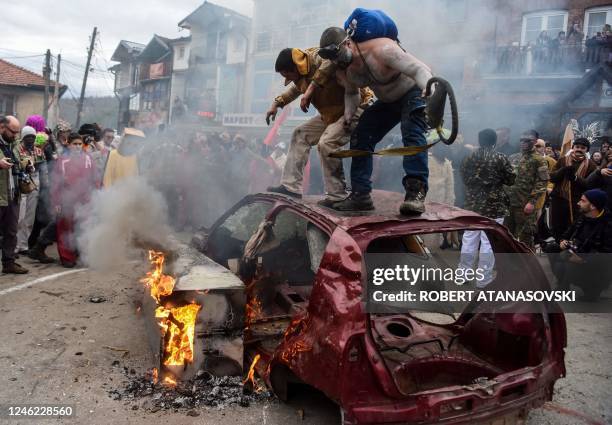 Participants jump on a burning car during the traditional burning of masks on the second day of a carnival marking the Orthodox Saint Vasilij Day in...