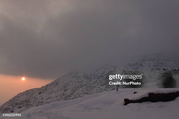 People walk on snow-covered hills after the fresh spell of snowfall on the outskirts of Srinagar, Indian Administered Kashmir on 14 January 2023. Two...