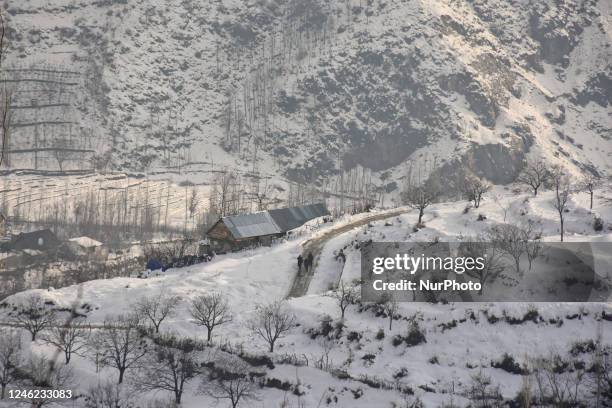 People walk on snow-covered hills after the fresh spell of snowfall on the outskirts of Srinagar, Indian Administered Kashmir on 14 January 2023. Two...