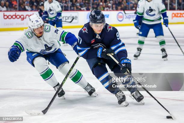 Cole Perfetti of the Winnipeg Jets plays the puck away from Ethan Bear of the Vancouver Canucks during second period action at Canada Life Centre on...