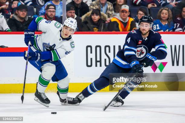 Ilya Mikheyev of the Vancouver Canucks plays the puck away from Neal Pionk of the Winnipeg Jets during second period action at Canada Life Centre on...