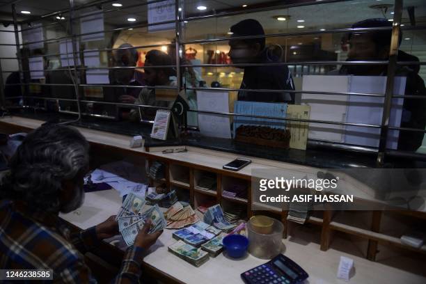 In this picture taken on January 10 a dealer counts US dollars at a money exchange market in Karachi. - Pakistan's usually bustling ports have ground...