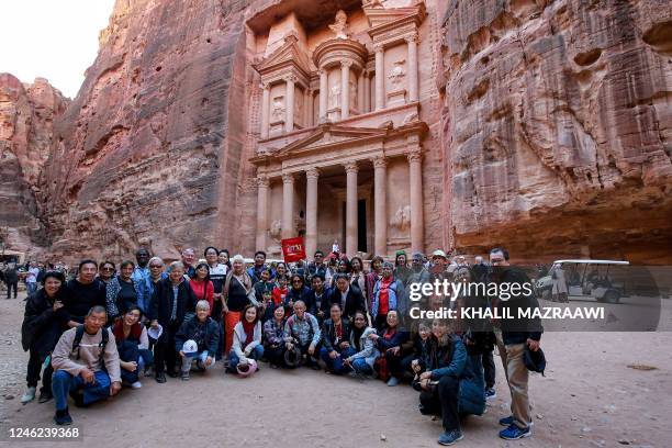 Tourists in a group pose for a photo before the site of the Treasury at the ruins of the ancient Nabatean city of Petra in southern Jordan on...