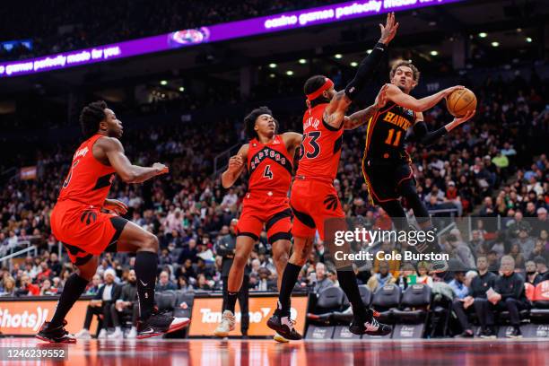 Trae Young of the Atlanta Hawks makes a pass as he's defended by Gary Trent Jr. #33, Scottie Barnes and O.G. Anunoby of the Toronto Raptors during...