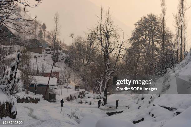 Residents walk along a snow covered bridge during sunset after a heavy snowfall in the outskirts of Srinagar. Avalanches were reported on Saturday in...