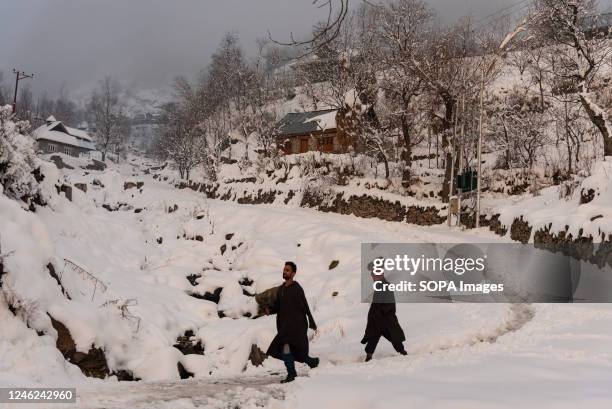 Kashmiri residents walk along a snow covered way after a heavy snowfall in the outskirts of Srinagar. Avalanches were reported on Saturday in Jammu...