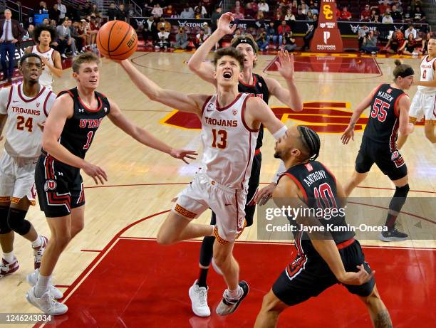 Drew Peterson of the USC Trojans drives past Ben Carlson, Branden Carlson and Marco Anthony of the Utah Utes in the first half at Galen Center on...
