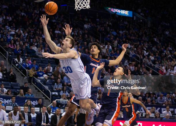 Dallin Hall of the Brigham Young Cougars shoots under pressure from JEvonPorter and Mike Mitchell Jr., #1 of the Pepperdine Waves during the second...