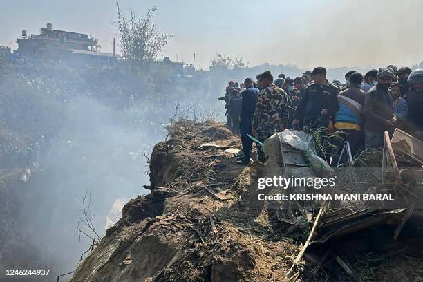 Rescuers and onlookers gather at the site of a Yeti Airlines plane crash in Pokhara on January 15, 2023. - An aircraft with 72 people on board...