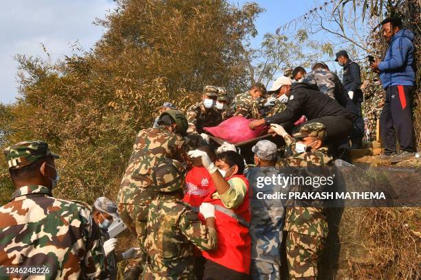 Graphic content / Rescuers carry the body of a victim who died in a Yeti Airlines plane crash in Pokhara on January 15, 2023. - At least 67 people...