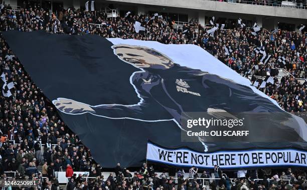 Newcastle fans hold a giant banner featuring an image of Newcastle United's English head coach Eddie Howe, ahead of the English Premier League...