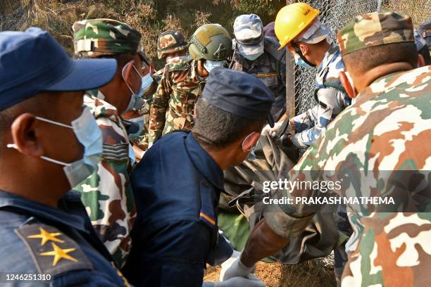 Graphic content / Rescuers carry the body of a victim who died in a Yeti Airlines plane crash in Pokhara on January 15, 2023. - At least 67 people...